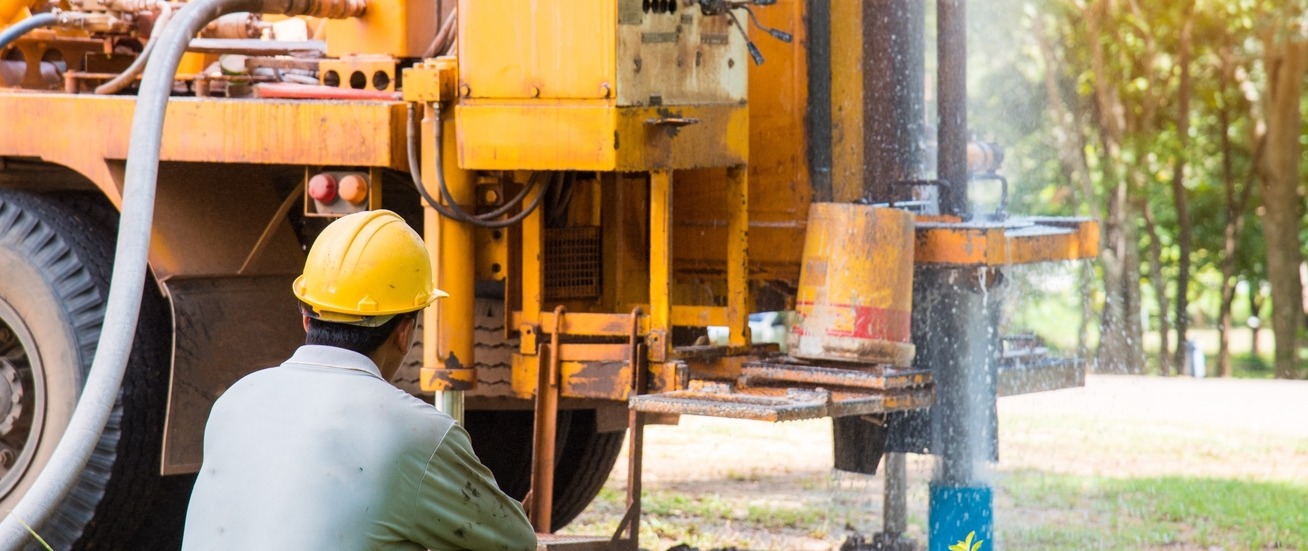 A man watching a drill rig drilling a water well